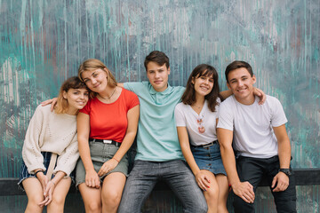 Summer holidays and teenage concept - group of smiling teenagers hanging out at colored wall