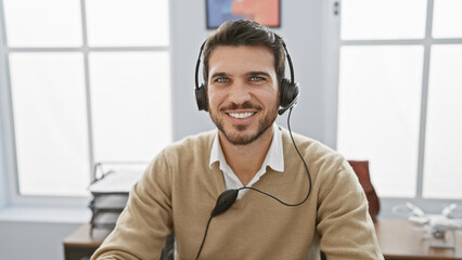 Smiling hispanic man with a headset in a bright office, conveying professionalism and friendly customer service.