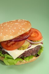 Burger with delicious patty on green background, closeup
