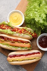 Delicious hot dogs with different toppings served on grey table, flat lay