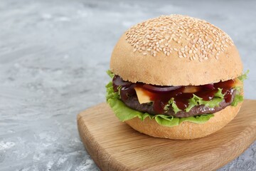 Delicious cheeseburger on grey table, closeup. Space for text
