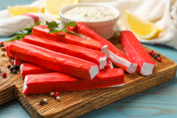 Tasty crab sticks, sauce and spices on light blue wooden table, closeup