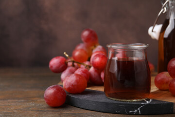 Wine vinegar in glass jar and grapes on wooden table