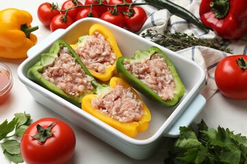 Raw stuffed peppers and ingredients on white table