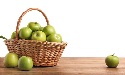 Ripe green apples in wicker basket on wooden table against white background. Space for text