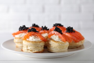 Delicious puff pastry with cream cheese, salmon and black caviar on white wooden table