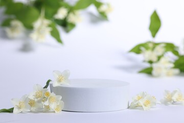 Presentation of product. Podium and beautiful jasmine flowers on white background