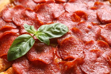 Tasty pepperoni pizza with basil as background, closeup