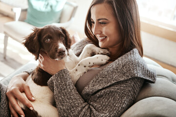 Love, relaxing and woman with dog on sofa bonding with pet in living room at apartment. Smile, animal and happy female person cuddle, hug and embrace puppy with care on couch in lounge at home.