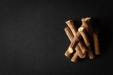 A pile of Dry Organic Liquorice or Mulethi (Glycyrrhiza glabra), isolated on a black background....
