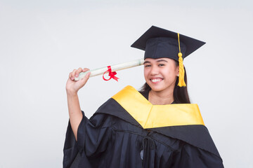 A happy female graduate of bachelor of science holding her diploma pointing it to her temple,...