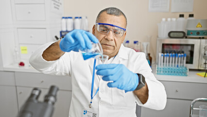 Mature hispanic man scientist analyzing liquids in lab