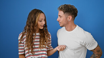 Fototapeta premium A couple in casual clothing engages intimately against a blue wall, depicting connection and companionship.