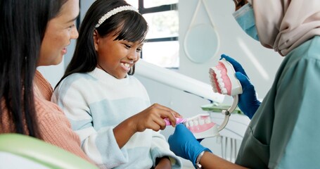 Girl, dentist or education on brushing teeth with toothbrush in practice or child friendly dentistry of tooth hygiene. Orthodontist, mother or kid by dental model or clean mouth in interactive lesson