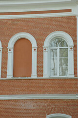 Fototapeta premium Element of the facade of a red brick building with white arched windows.