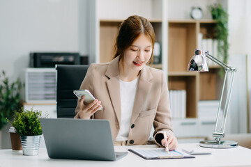 Asian Businesswoman Analyzing Finance on Tablet and Laptop at modern Office Desk tax