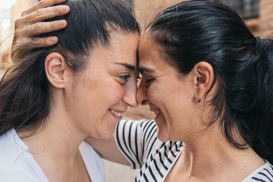 Intimate moment between same-sex couple. Close-up ortrait of a smiling lgbt couple embracing and touching foreheads