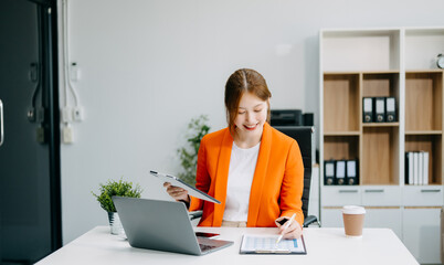 Asian Businesswoman Analyzing Finance on Tablet and Laptop at modern Office Desk tax