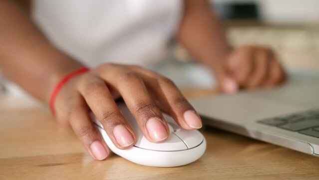 A close up view of an African American woman hand clicking the computer mouse button while she is working or studying.