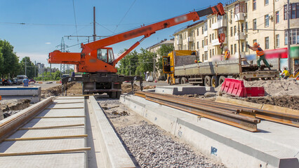 Naklejka premium Orange construction telescopic mobile crane unloading tram rails from truck timelapse.