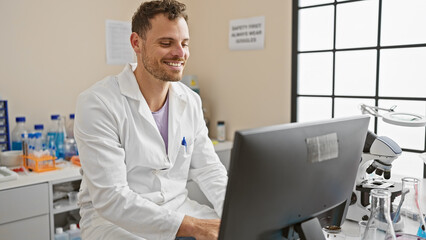 Smiling man in lab coat working with computer in bright laboratory setting