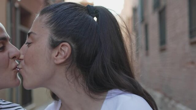 Tender kiss between women in urban alley. Loving same-sex couple shares a kiss in the tranquility of a city street