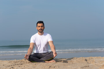 Man and woman doing yoga at the beach