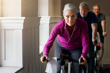 Woman, riding and bicycle for fitness with headphones at gym spin class, training and workout...