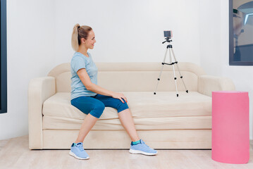 Young athletic healthy female blogger recording video about home training. Svelte figure: Girl exercises solo in a gym, embodying dedication to fitness