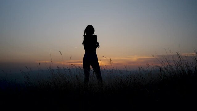 Silhouette of a happy woman taking off her clothes and dancing in the nature.Freedom concept
