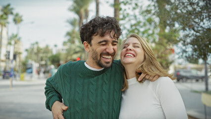 Obraz premium Joyful couple embracing and laughing together on a city street, depicting love and happiness in an urban outdoor setting.