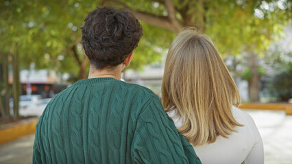 A man and woman, embraced in an urban park, showcase a moment of love and companionship amidst the greenery.