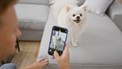 Young caucasian man sitting on the floor at home, relaxed and focused while making a photo of his...