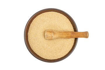 Dry yellow amaranth grains in a brown ceramic bowl on a white background