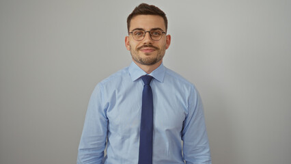 Handsome young hispanic man with beard and glasses in a blue dress shirt and tie, posing over an isolated white background.