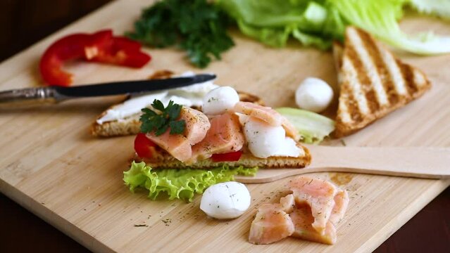 fried toast with salmon, cream cheese, salad, on a wooden table .