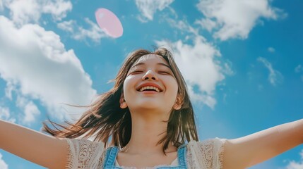 Naklejka premium Beautiful asian girl with arms wide open and huge smile on her face against blue sky