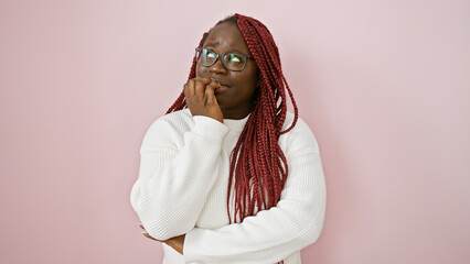 Thoughtful african american woman with braids posing against a pink background