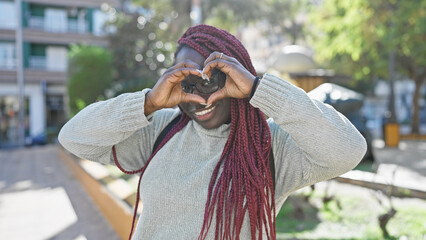 African american woman with braids making heart gesture in park
