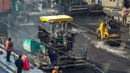 Fototapeta premium Workers operating asphalt paver machines during road construction and repairing works timelapse