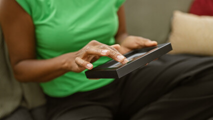 African american woman examining a photo frame indoors, conveying a sense of nostalgia and memory.