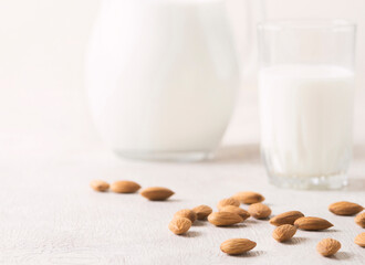Alternative milk of almonds in a glass and glass jug on a wooden background. copy space