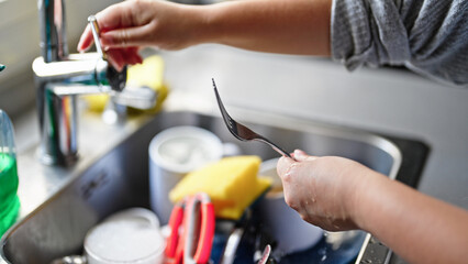 Young beautiful hispanic woman washing plates at the kitchen