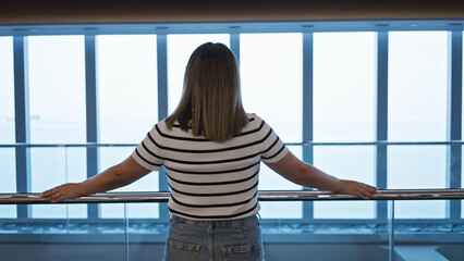 A young adult brunette woman enjoys the ocean view aboard a modern luxury cruise ship.
