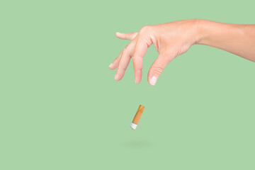 female hand throwing a cigarette on isolated green background