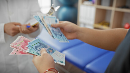 Obraz premium Two men exchange chinese yuan in an indoor clinical setting, highlighting healthcare payment.