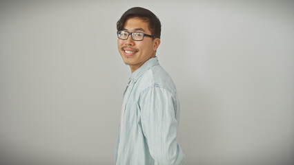 A young asian man with glasses stands smiling against a white background in casual clothing.