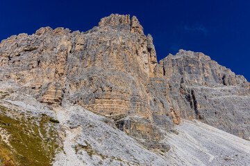 Dolomites beautiful alpine rock tower summits under blue sky in summer. Italian Alps mountains scenic landscape of rocky climbing walls in the high altitude majestic view of the cliff and green valley