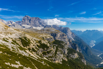 Dolomites beautiful alpine rock tower summits under blue sky in summer. Italian Alps mountains scenic landscape of rocky climbing walls in the high altitude majestic view of the cliff and green valley