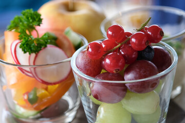 Three small glass bowls filled with fruit, including apples, grapes